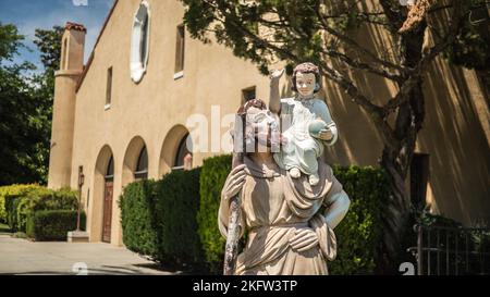 Une statue de sculpture de Saint Joseph tenant bébé Jésus sur l'épaule dans la cour d'une église Banque D'Images