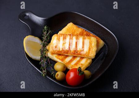 Fromage halloumi grillé dans une casserole noire avec olives, tomates, concombres, thym et citron. Fromage traditionnel de la Méditerranée orientale. Banque D'Images