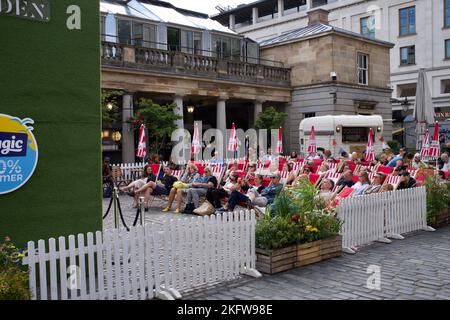 Public assis devant un bar à Covent Garden, Londres et regardant sur un écran un match de tennis au court central de Wembley 2022. Relaxant et buvant. Banque D'Images