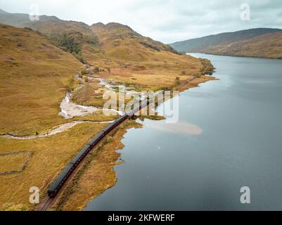 Train à vapeur passant par un Loch dans les Highlands écossais Banque D'Images