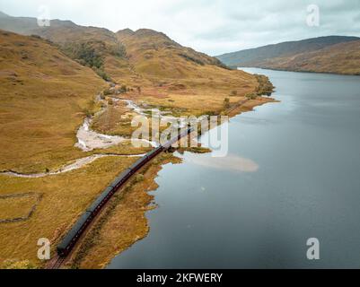 Train à vapeur passant par un Loch dans les Highlands écossais Banque D'Images