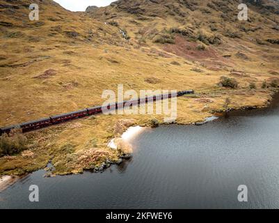 Train à vapeur passant par un Loch dans les Highlands écossais Banque D'Images