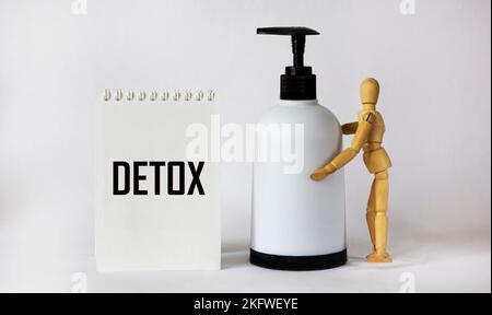 Mot DETOX sur bloc-notes et fond blanc, concept Detox. Il y a une poupée en bois avec un distributeur Banque D'Images