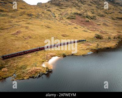 Train à vapeur passant par un Loch dans les Highlands écossais Banque D'Images