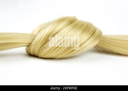Boucles de cheveux ondulées blondes nouées sur fond blanc. Mèche de cheveux blond nouée sur fond blanc Banque D'Images