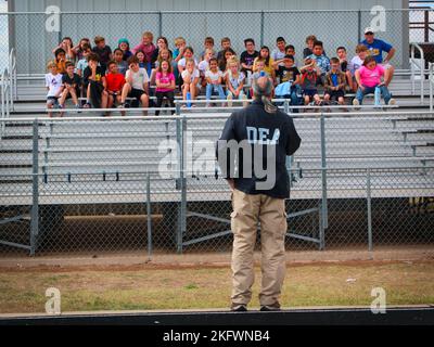 AUSTIN, Texas — Un agent spécial de la U.S. Drug Enforcement Administration parle avec des enfants du district scolaire indépendant de VeriBEST 11 octobre 2022, à VeriBEST, Texas, avec le soutien du Texas National Guard joint CounterDrug Task Force qui a apporté un hélicoptère LUH-72 Lakota et leur mascotte, « Enney the Eagle », pour visiter l'école pendant les activités de la semaine du ruban rouge. Chaque année, le programme Texas CounterDrug soutient les activités de sensibilisation et de prévention du ruban rouge de DEA dans les écoles de l’État. Banque D'Images