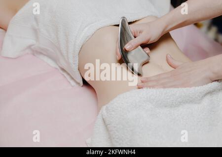 Massage avec une palette de massage spéciale, pétrissage des points de déclenchement dans l'abdomen, gros plan. Massage des lames. Vue latérale. Placer pour le texte Banque D'Images