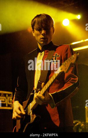 DÉBUT DU CONCERT, FRANZ FERDINAND, 2004 : un très jeune ALEXANDER KAPRANOS, chanteur et guitariste avec le groupe écossais FRANZ FERDINAND en tournée la semaine de sortie de leur premier album éponyme lors du NME Tour à Cardiff Students' Union, le 8 février 2004. Photographie : ROB WATKINS. INFO : Franz Ferdinand est un groupe de rock écossais formé en 2002, connu pour son son revival post-punk accrocheur et dansant. Leur premier album, 'Franz Ferdinand', et des tubes comme 'Take me Out' les ont catapultés à une renommée internationale et à une influence significative dans le rock indépendant. Banque D'Images