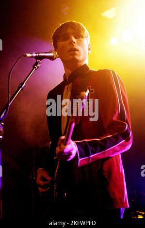 DÉBUT DU CONCERT, FRANZ FERDINAND, 2004 : un très jeune ALEXANDER KAPRANOS, chanteur et guitariste avec le groupe écossais FRANZ FERDINAND en tournée la semaine de sortie de leur premier album éponyme lors du NME Tour à Cardiff Students' Union, le 8 février 2004. Photographie : ROB WATKINS. INFO : Franz Ferdinand est un groupe de rock écossais formé en 2002, connu pour son son revival post-punk accrocheur et dansant. Leur premier album, 'Franz Ferdinand', et des tubes comme 'Take me Out' les ont catapultés à une renommée internationale et à une influence significative dans le rock indépendant. Banque D'Images