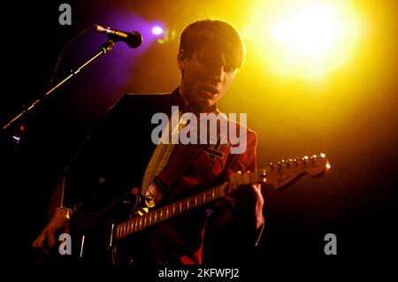 DÉBUT DU CONCERT, FRANZ FERDINAND, 2004 : un très jeune ALEXANDER KAPRANOS, chanteur et guitariste avec le groupe écossais FRANZ FERDINAND en tournée la semaine de sortie de leur premier album éponyme lors du NME Tour à Cardiff Students' Union, le 8 février 2004. Photographie : ROB WATKINS. INFO : Franz Ferdinand est un groupe de rock écossais formé en 2002, connu pour son son revival post-punk accrocheur et dansant. Leur premier album, 'Franz Ferdinand', et des tubes comme 'Take me Out' les ont catapultés à une renommée internationale et à une influence significative dans le rock indépendant. Banque D'Images