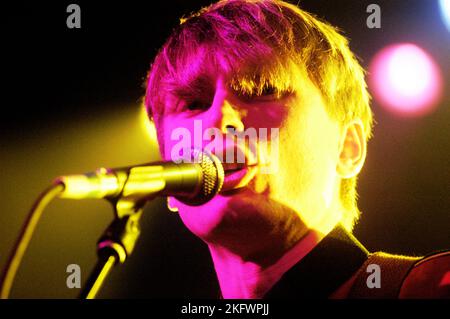 DÉBUT DU CONCERT, FRANZ FERDINAND, 2004 : un très jeune ALEXANDER KAPRANOS, chanteur et guitariste avec le groupe écossais FRANZ FERDINAND en tournée la semaine de sortie de leur premier album éponyme lors du NME Tour à Cardiff Students' Union, le 8 février 2004. Photographie : ROB WATKINS. INFO : Franz Ferdinand est un groupe de rock écossais formé en 2002, connu pour son son revival post-punk accrocheur et dansant. Leur premier album, 'Franz Ferdinand', et des tubes comme 'Take me Out' les ont catapultés à une renommée internationale et à une influence significative dans le rock indépendant. Banque D'Images