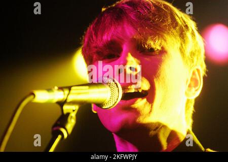 DÉBUT DU CONCERT, FRANZ FERDINAND, 2004 : un très jeune ALEXANDER KAPRANOS, chanteur et guitariste avec le groupe écossais FRANZ FERDINAND en tournée la semaine de sortie de leur premier album éponyme lors du NME Tour à Cardiff Students' Union, le 8 février 2004. Photographie : ROB WATKINS. INFO : Franz Ferdinand est un groupe de rock écossais formé en 2002, connu pour son son revival post-punk accrocheur et dansant. Leur premier album, 'Franz Ferdinand', et des tubes comme 'Take me Out' les ont catapultés à une renommée internationale et à une influence significative dans le rock indépendant. Banque D'Images