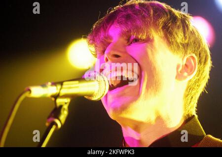 DÉBUT DU CONCERT, FRANZ FERDINAND, 2004 : un très jeune ALEXANDER KAPRANOS, chanteur et guitariste avec le groupe écossais FRANZ FERDINAND en tournée la semaine de sortie de leur premier album éponyme lors du NME Tour à Cardiff Students' Union, le 8 février 2004. Photographie : ROB WATKINS. INFO : Franz Ferdinand est un groupe de rock écossais formé en 2002, connu pour son son revival post-punk accrocheur et dansant. Leur premier album, 'Franz Ferdinand', et des tubes comme 'Take me Out' les ont catapultés à une renommée internationale et à une influence significative dans le rock indépendant. Banque D'Images