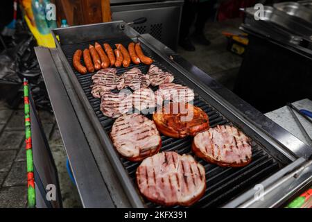 Détails de faible profondeur de champ (mise au point sélective) avec saucisses de porc et steaks cuisant sur un barbecue, dans un marché agricole européen, à Bucarest Banque D'Images