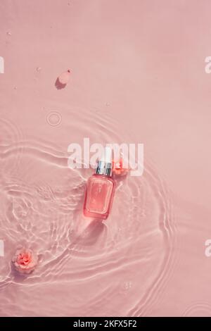 Flacon cosmétique avec sérum, collagène, huile dans l'eau et roses roses. Concept cosmétique hydratant pour les soins de la peau Banque D'Images