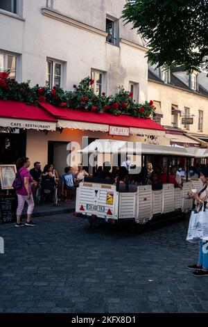 Une photo verticale d'un tramway touristique avec des personnes se trouvant à Montmartre, Paris, France Banque D'Images