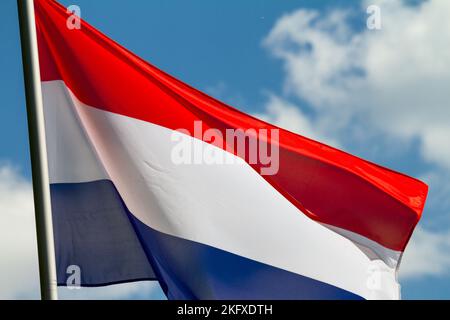 Drapeau des pays-Bas agitant dans le vent sur le mât contre le ciel avec des nuages le jour ensoleillé, gros plan Banque D'Images