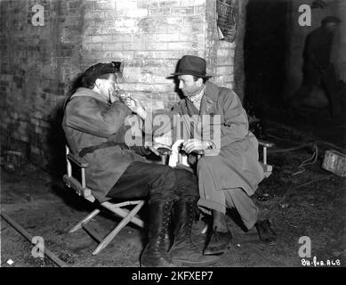 Le réalisateur MICHAEL CURTIZ allume une cigarette pour PAUL MUNI sur un écran de musique candide pendant le tournage de LA FUREUR NOIRE 1935 le réalisateur MICHAEL CURTIZ l'histoire originale Jan Volkanik par le juge Michael A. Musmanno First National Pictures / Warner Bros. Banque D'Images