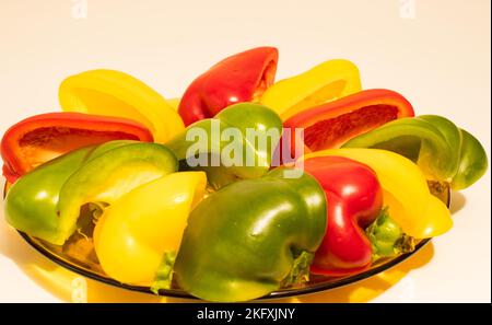 Poivron coloré 22.11.2022 Bialystok Pologne. Assiette transparente en verre et fruits de poivrons doux et colorés sur fond blanc. Banque D'Images