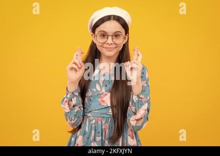 Adolescent heureux, émotions positives et souriantes. Bonne adolescente croise les doigts, anticipe entendre de bonnes nouvelles, isolé fond jaune. Heureux Banque D'Images