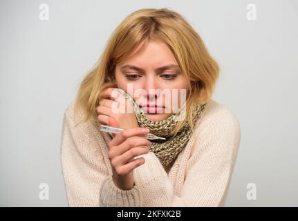 La femme se sent mal éternuée. Une fille en foulard tient le thermomètre et le mouchoir de près. Mesurer la température. Concept haute température. Fièvre de pause Banque D'Images