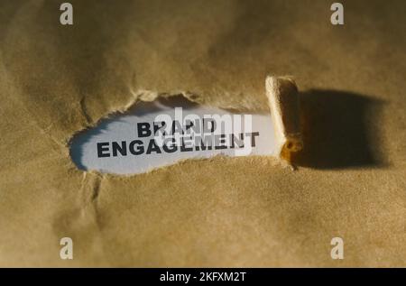 Concept économique et commercial. Papier déchiré au milieu de la feuille, à l'intérieur sur un fond blanc l'inscription - ENGAGEMENT DE LA MARQUE Banque D'Images