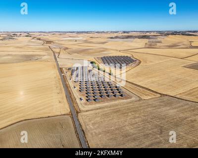 Vue aérienne d'une centrale photovoltaïque dans la campagne en dehors de Valladolid en Espagne, avec quelques moulins à vent en arrière-plan. Banque D'Images