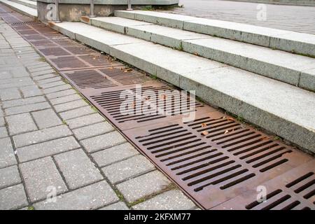 La grille d'égout sur le trottoir est rouillée de près Banque D'Images