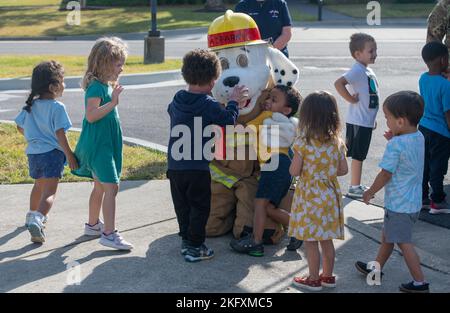 Un enfant du Centre pour le développement de l'enfant reçoit un câlin de Sparky le chien d'incendie, la mascotte officielle de la National Fire protection Association pendant la tournée de la semaine de prévention des incendies à la CDC sur la base aérienne de Keesler, Mississippi, le 13 octobre 2022. Tout au long de la semaine, le Service des incendies de Keesler a mené des exercices d'incendie aléatoires, visité diverses installations avec Sparky le chien d'incendie, transmis des renseignements sur la sécurité incendie et des chapeaux d'incendie pour les enfants. Banque D'Images