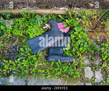 Bottes Wellington noires jetées et gants en caoutchouc rose Banque D'Images