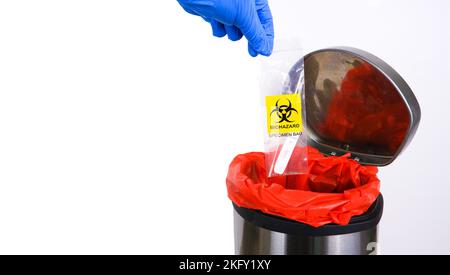 Les déchets infectieux sont jetés dans la poubelle rouge des déchets infectieux par la main du médecin avec un espace de copie sur fond blanc Banque D'Images