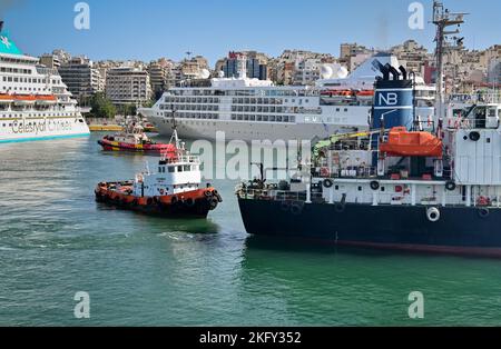 Pirée, Athènes, Grèce - juin 2022 : petit remorqueur escortant un navire pétrolier utilisé pour ravitailler de plus grands navires dans le port du Pirée. Banque D'Images