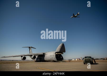 Les aviateurs américains affectés à l'escadron d'intervention en cas d'urgence 921st effectuent un déchargement à partir d'un C-5M Super Galaxy alors que les moteurs fonctionnent tandis qu'un KC-10 Extender vole au-dessus pendant l'exercice Dragon Spark à la base aérienne de Travis, en Californie, le 14 octobre 2022. L'exercice Dragon Spark a offert aux unités de l'aile 60th de la mobilité aérienne et de l'aile 621st de l'intervention en cas d'urgence l'occasion de synchroniser les opérations en vue d'une catastrophe nationale. Banque D'Images