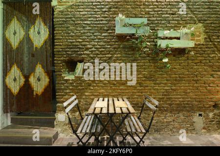 Table à manger avec bancs pliants en bois et en métal dans un restaurant de style bohème aux murs en briques apparentes Banque D'Images