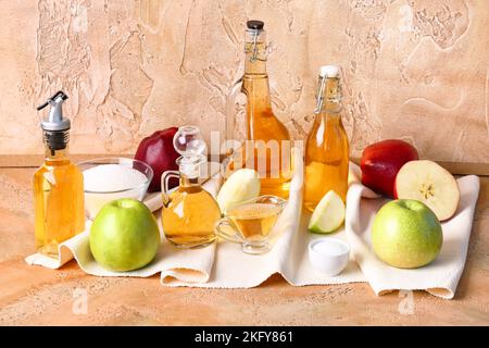 Composition avec bouteilles de vinaigre de cidre de pomme, fruits, sel et sucre sur fond de couleur Banque D'Images