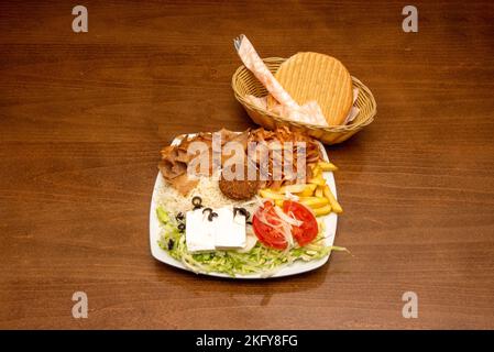 Plat typique de kebab avec du falafel, des oignons, du riz blanc, de la viande d'agneau et de la laitue, ainsi qu'une portion de frites sur une assiette blanche et du pain avec de la viande coupée Banque D'Images