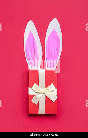 Oreilles de lapin en papier avec cadeau de Noël sur fond rouge Banque D'Images