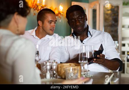 Réunion amicale autour d'un dîner avec wine in restaurant Banque D'Images