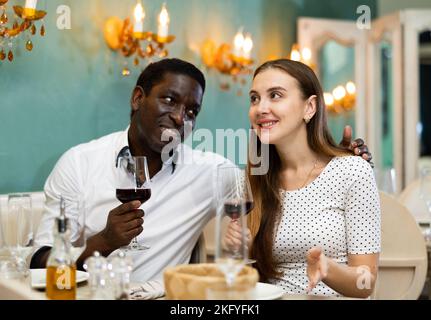 Paire d'amour sourire positif profiter de repas du soir et la conversation au restaurant confortable Banque D'Images