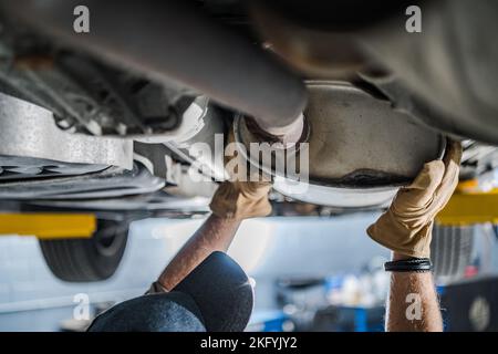 Inspection par un mécanicien du convertisseur catalytique du véhicule pendant la vérification programmée du système d'échappement du véhicule. Thème d'entretien automobile. Banque D'Images