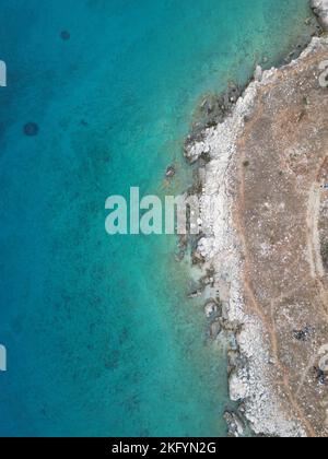 Vue verticale en haut de l'eau de mer bleu vif sur une côte rocheuse en Croatie Banque D'Images