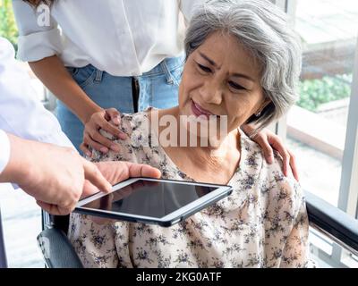 Portrait d'une femme âgée souriante, patients en fauteuil roulant avec assistant, prenez-la pour rencontrer un médecin, un comprimé d'utilisation masculine, discutant de son dossier de traitement médical Banque D'Images