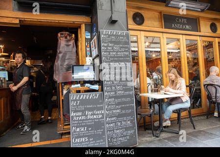 Melbourne Victoria, jeune femme blonde assise seule livre lisant dans la rue Degraves dans un café dans cette ruelle de Melbourne, Victoria, Australie Banque D'Images