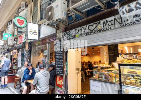 Les amis masculins de la piste de Melbourne discutent dans un café de la piste Center place, Victoria, Australie, à côté du café Hells Kitchen Banque D'Images