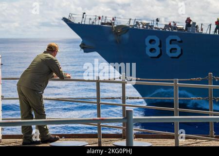 221020-N-AT895-1014 OCÉAN PACIFIQUE (OCT 20, 2022) Un marin de la marine américaine regarde comme le destroyer de missile guidé de classe Arleigh Burke USS Shoup (DDG 86) tire à côté du porte-avions USS Nimitz (CVN 68) pour un ravitaillement en mer. Le groupe de grève des transporteurs Nimitz est en cours de préparation pour un déploiement à venir. Banque D'Images