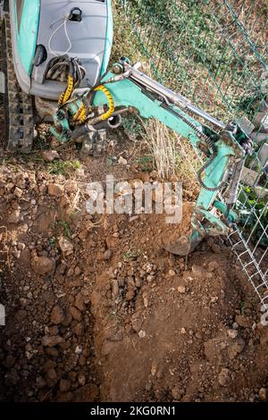 Une minipelle creuse une tranchée pour poser les tuyaux. Gros plan d'une pelle hydraulique creusant une tranchée profonde. Une pelle hydraulique creuse une tranchée dans la campagne pour déposer un Banque D'Images