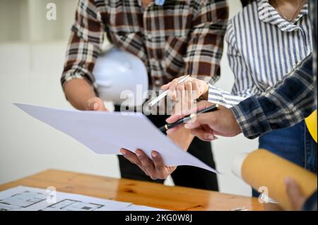 Équipe d'ingénieurs et d'architectes asiatiques professionnels discutant, vérifiant le plan et travaillant ensemble au bureau. Plan rogné Banque D'Images