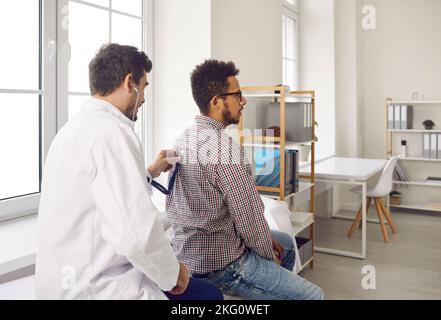 Pendant le rendez-vous médical, le médecin écoute les poumons du patient avec un stéthoscope pour la respiration sifflante. Banque D'Images