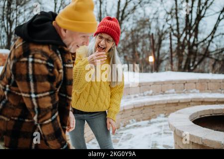 Couple senior s'amusant à l'extérieur pendant le broyage du bois ensemble devant leur maison. Banque D'Images