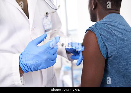 C'est un petit aïe avec d'énormes avantages. Gros plan d'un patient mâle recevant une injection d'un médecin. Banque D'Images